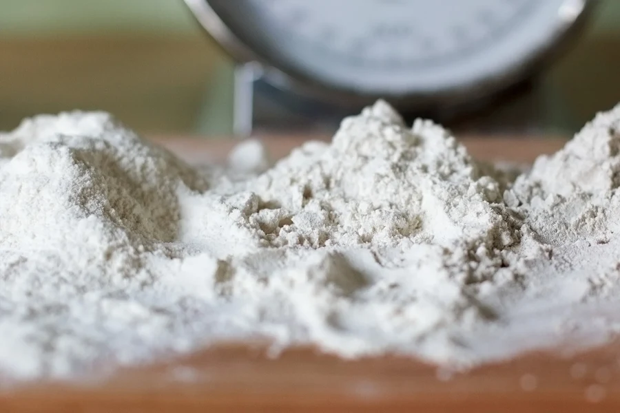 Tas de farine blanche sur un plan de travail devant une balance de cuisine