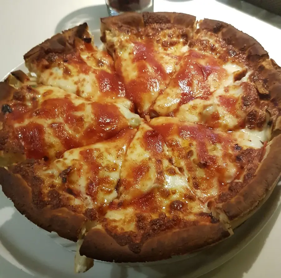 Une deep dish pizza découpée, bord haut et fromage visible. Photo Telluride, CC BY-SA 3.0, Wikimedia Commons.