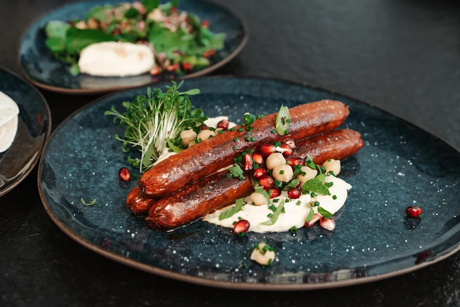 Merguez grillées, dressées sur une assiette, la garniture centrale d’une pizza orientale